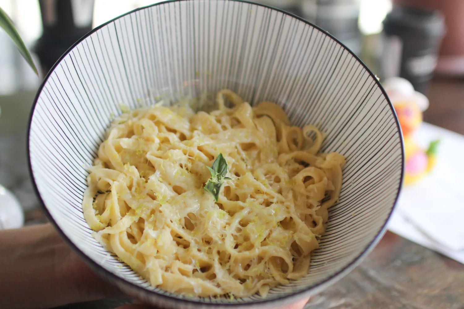 Lemon garlic pasta topped with grated cheese, lemon zest, and fresh basil