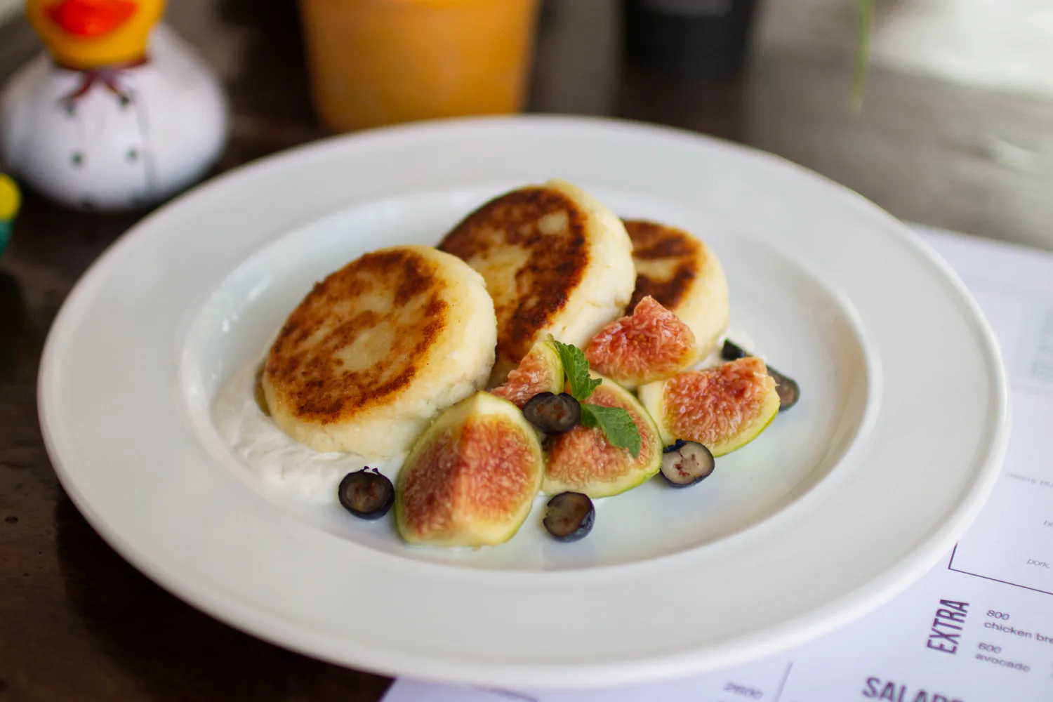 Syrniki served with figs, blueberries, mint, and jam